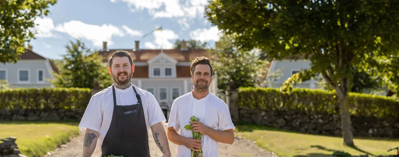 två kockar framför herrgårdsbyggnad