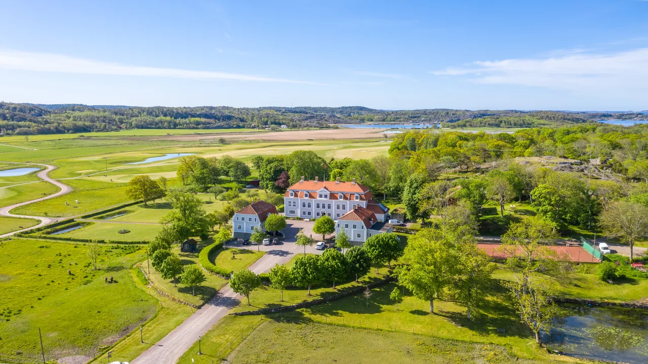 drönarbild herrgård, golfbana och gröna träd, hav i bakgrunden