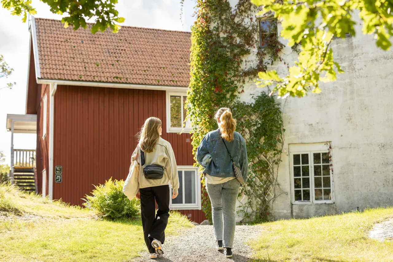 två kvinnor promenerar mot röd byggnad