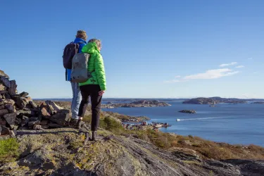 två personer med ryggsäck, klippor, hav